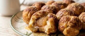 Яблочный манки брэд omena-monkeybread: разломанный шарик с начинкой из яблока, посыпанный корицей и сахаром, политый карамелью на цветной тарелке